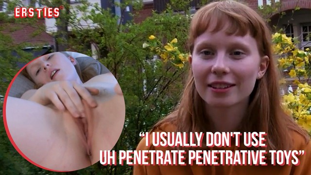 Smiling ginger in orange hoodie interviews in garden courtyard by brick wall